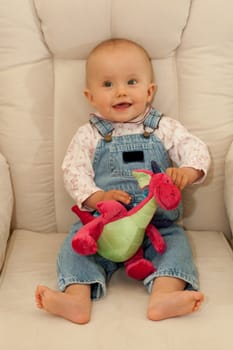 Little caucasian baby girl sitting on a chair.