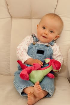 Little caucasian baby girl sitting on a chair.