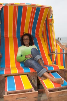 Pretty black woman sitting on a very colorful beachchair