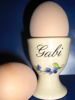 two boiled eggs, one of them in a fawn ceramic egg-cup with small blue flowers on it