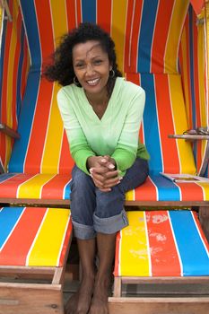 Happy black woman sitting outdoors in the beachchair