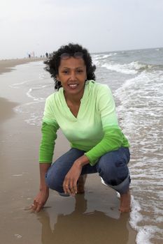 Pretty black woman kneeling by the edge of the waterside