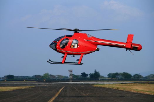 rotorless red helicopter hovering over an airfield
