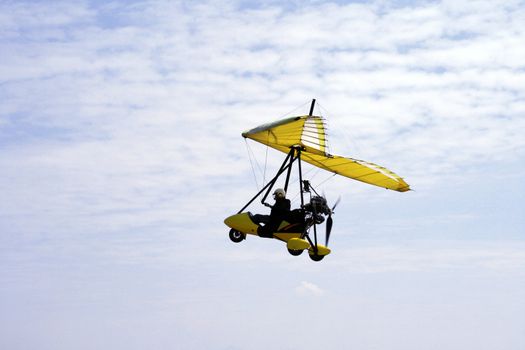 sideview of an ultralight aircraft against a blue sky
