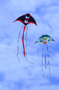 two giant colorful kites flying against a blue sky
