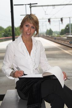 Businesswoman working at the station while waiting for the train to arrive