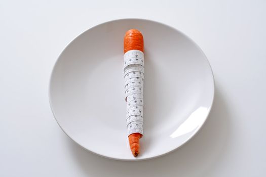 Carrot wrapped with measuring tape on a plate