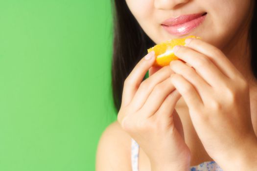 A woman eating a slice of orange