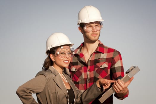 Handsome man and pretty woman outdoors wearing protective hardhats