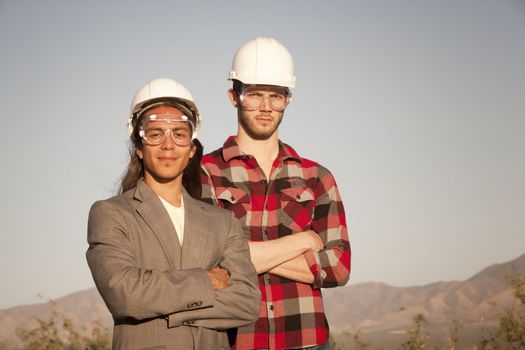 Two handsome men outdoors wearing protective hardhats