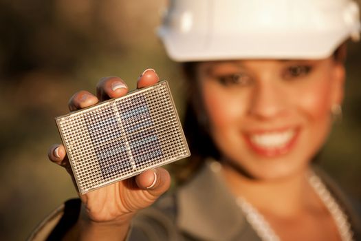 Pretty young woman wearing hardhat with small solar panel in hand