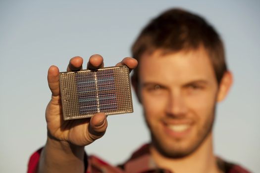Handsome young man with small solar panel in hand