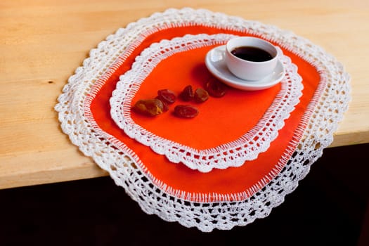 A coffee cup and several dried fruits on two orange napkins
