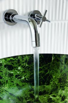 Contemporary bathroom: water running out of beautiful designer wall mounted faucet into tempered glass, fake green marble, vessel sink.