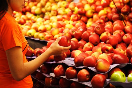 A woman shopping for apples at a grocery store