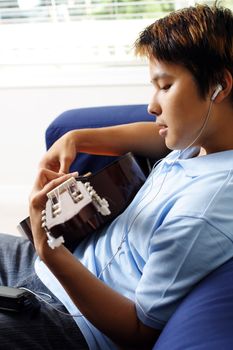 A man playing a guitar while listening to music