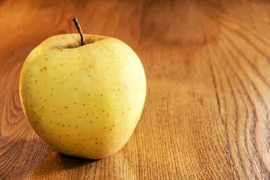 Golden delicious apple on kitchen wooden table with copy space.