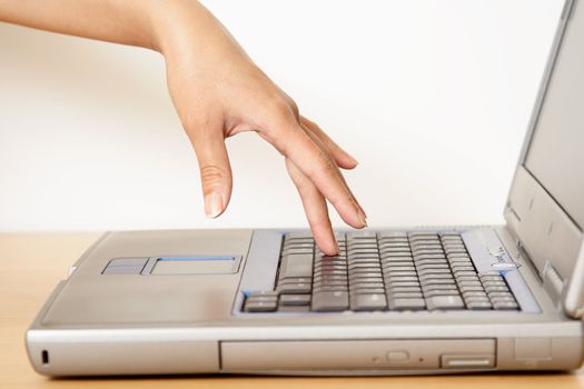 A woman's finger touching a laptop's keyboard