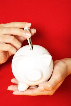 A woman depositing money into a piggy bank