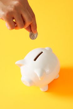 A woman saving a coin into a piggy bank