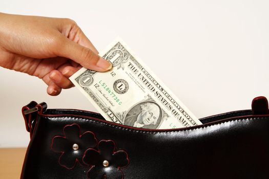 A woman taking out one dollar bill from a purse