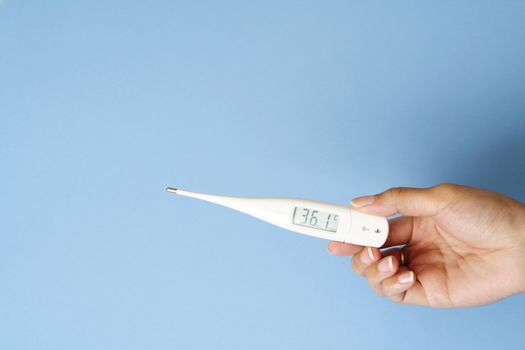 A woman's hand holding a digital body thermometer