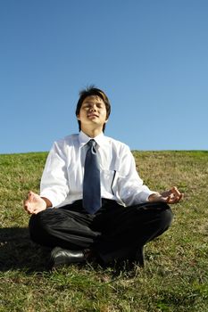 A businessman meditating in a park