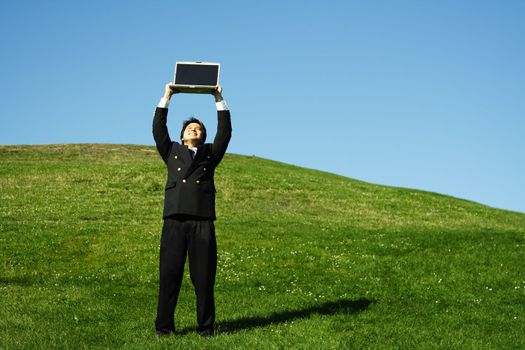 Happy businessman holding laptop high in the air