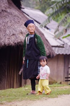A grandmother Dao black and her granddaughter. Poverty of the people of North Vietnam, is that parents are often left very far to findwork outside the fields of culture arid mountains. The grandparentsthen take care of small children