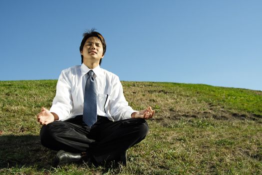 A businessman meditating in a park