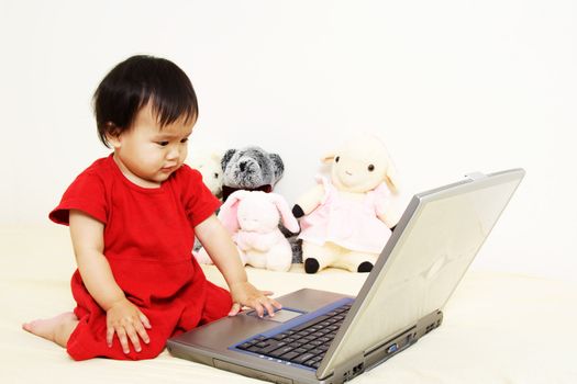 A cute little baby girl playing with laptop