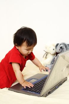 A cute little baby girl playing with a laptop