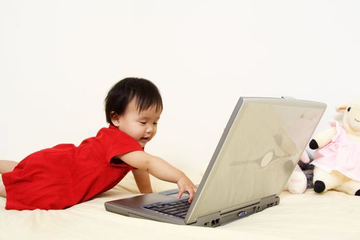 A cute baby girl playing with a laptop