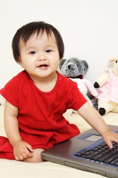 A cute little baby girl playing with a laptop