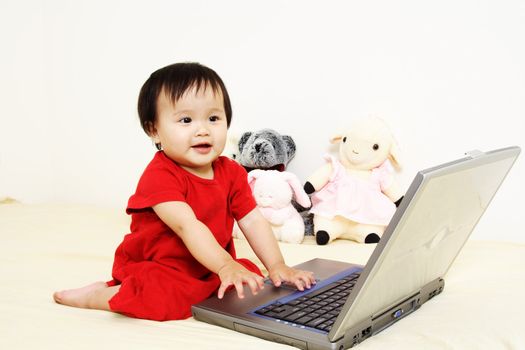 A cute little baby girl playing with a laptop