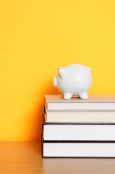 A piggy bank on top of a stack of books, can be used for saving for college design