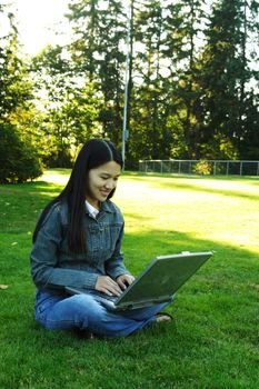 A girl sitting in a park with laptop