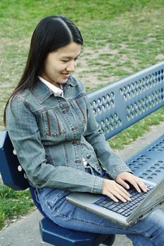 A girl working on her laptop at a park