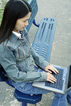 A girl working on her laptop at a park