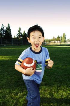 A happy boy playing football outdoor