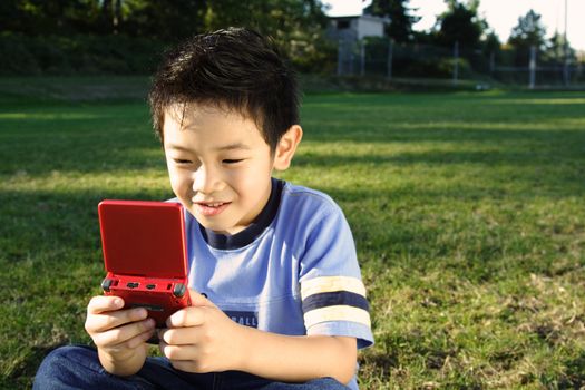 A boy playing video game at a park