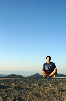 A man meditating on top of a mountain