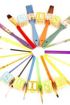 paintbrushes in the shape os sunshine and spelled with childrens blocks.