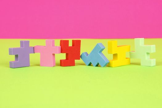 Bright colored puzzle piece erasers in a row with a pink and green background.