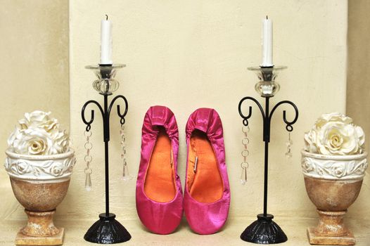 pink wedding shoes next to candle holders on mantle piece