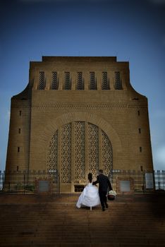 Bridal couple walking up big building stairs