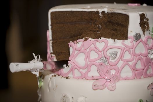 Knife in cut wedding cake with pink hearts