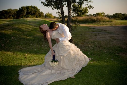 just married couple with groom kissing bride in the cleavage on a sunny day