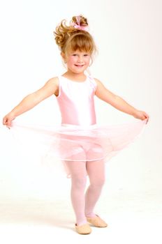 Little smiley girl wearing a pink ballet outfit is dancing holding her dress