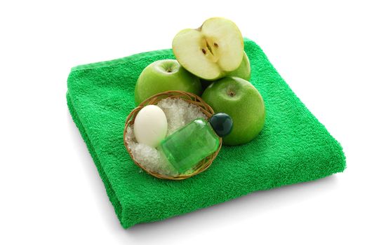 Apple flavored SPA set including soap, salt and shampoo on green towel 